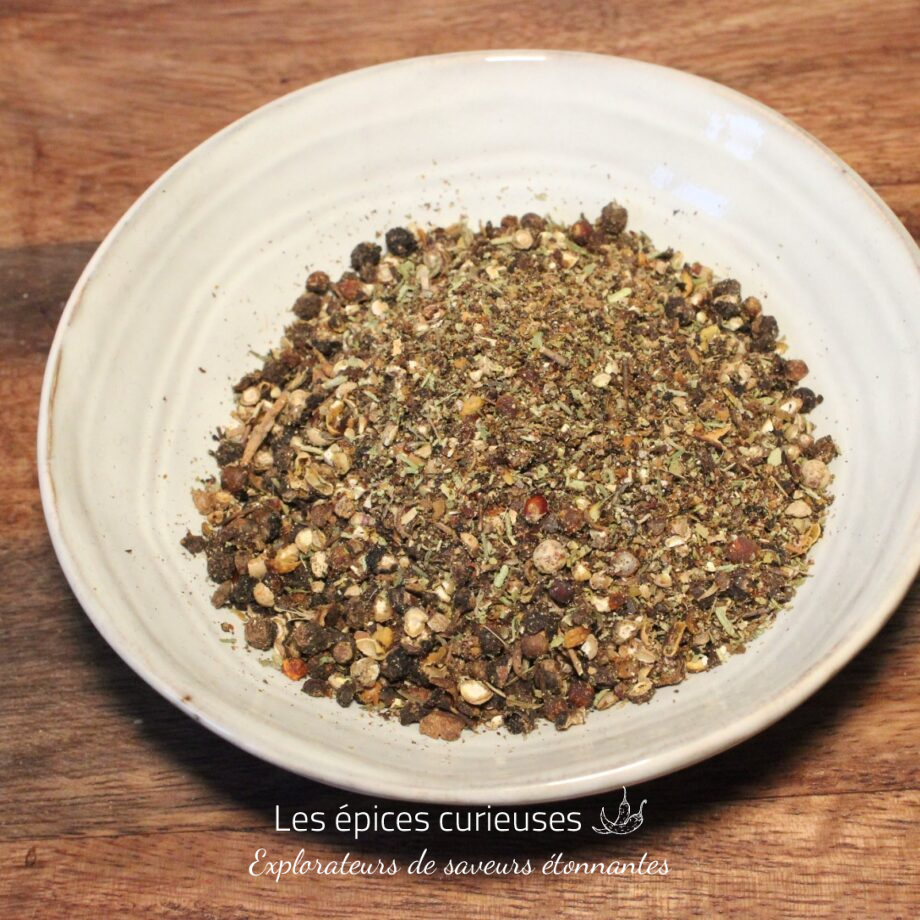 Assortiment d'épices dans un bol blanc sur une table en bois, parfait pour la cuisine maison.