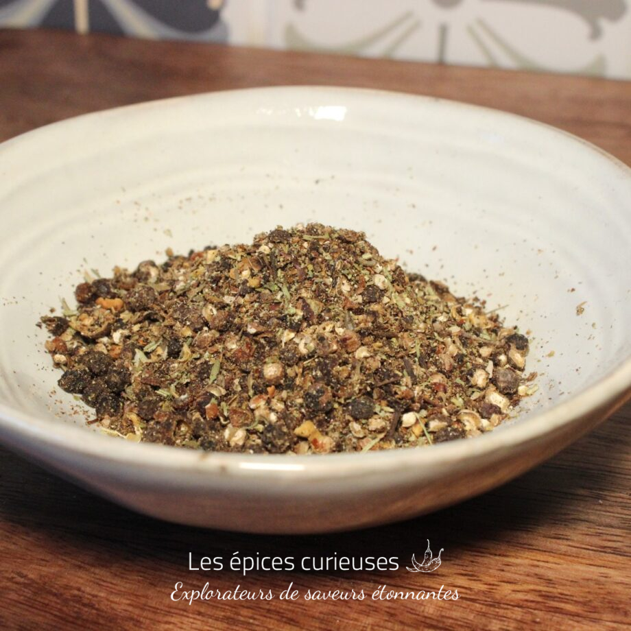 Assiette de mélange d'épices artisanales sur une table en bois pour une cuisine savoureuse et aromatique.