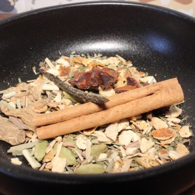 Un mélange d'épices aromatiques dans un bol noir, avec de la cannelle, de l'anis étoilé et des herbes séchées.