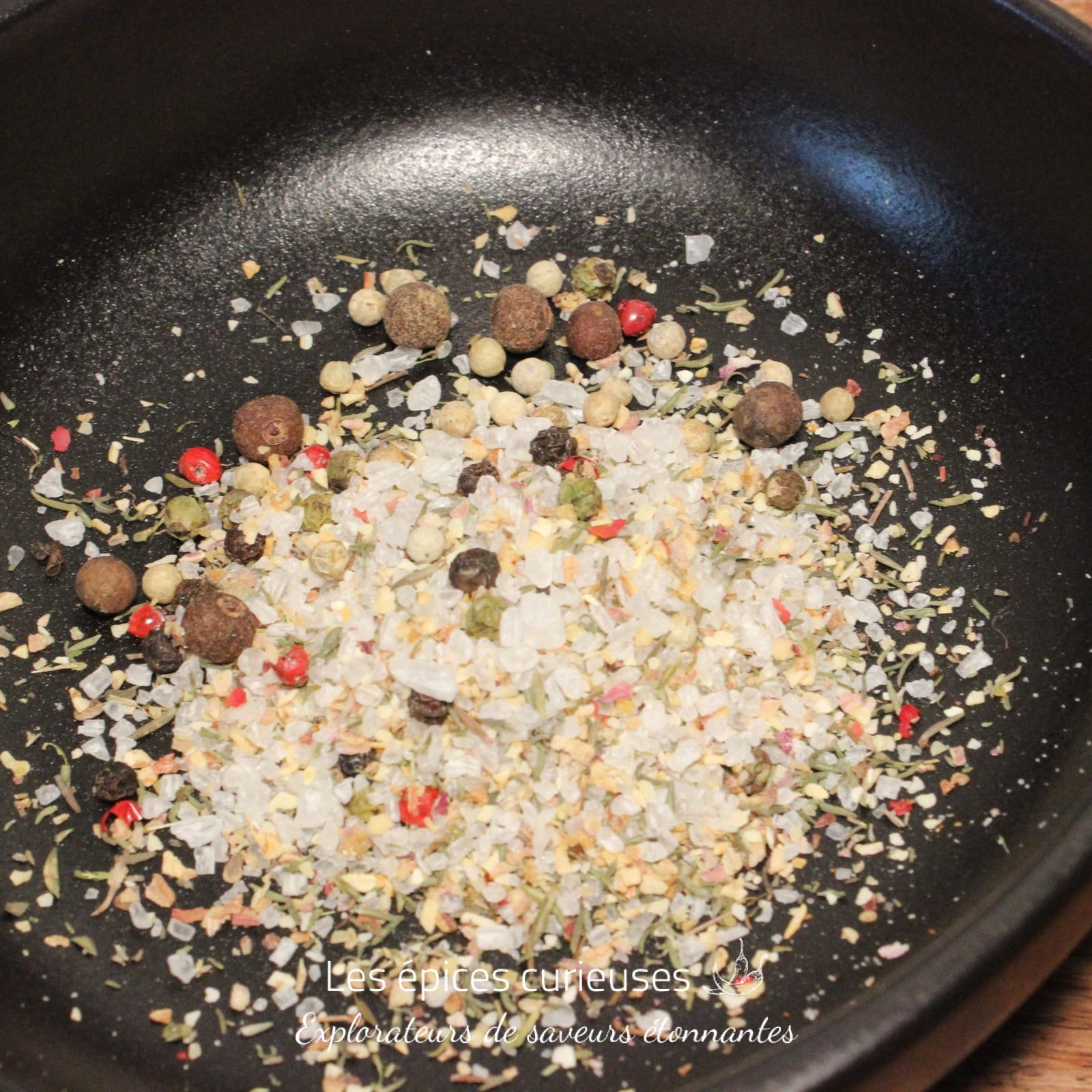 Mélange d'épices et de sel dans une poêle noire pour rehausser vos plats avec saveurs et arômes.