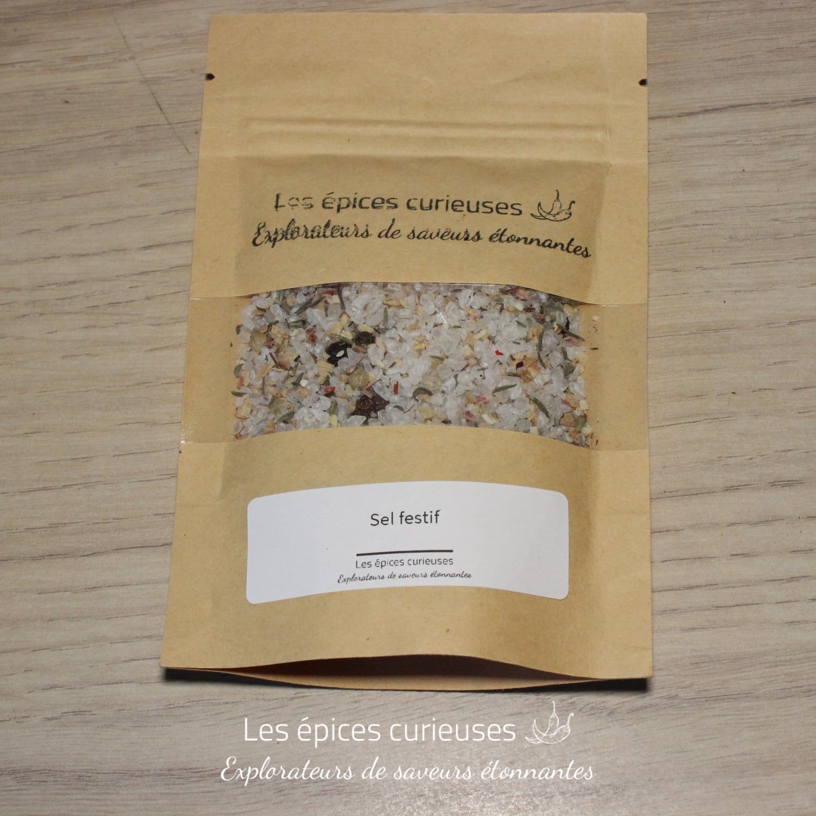 Sachet de sel festif Les Épices Curieuses sur une table en bois, saveurs uniques pour vos plats.
