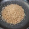 Un tas de sucre brun naturel sur une assiette noire lisse.