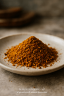 Monticule d'épices colorées sur une assiette blanche, prêt à rehausser vos plats de saveurs exotiques.