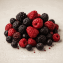 Assortiment de baies fraîches : framboises, mûres et myrtilles sur fond neutre.