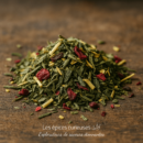 Mélange de thé vert avec baies rouges et herbes séchées sur une table en bois.