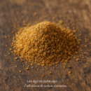 Tas de sucre brun sur fond bois, mise au point rapprochée, texture granuleuse et naturelle.