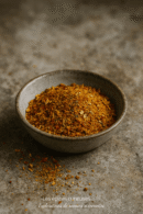 Bol de mélange d'épices colorées sur fond rustique, idéal pour assaisonner vos plats savoureux.