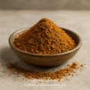 Bol en céramique rempli de poudre d'épices brun orangé sur une surface en pierre.