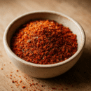 Bol de piment en poudre sur planche en bois, épice rouge vive pour cuisine intense.