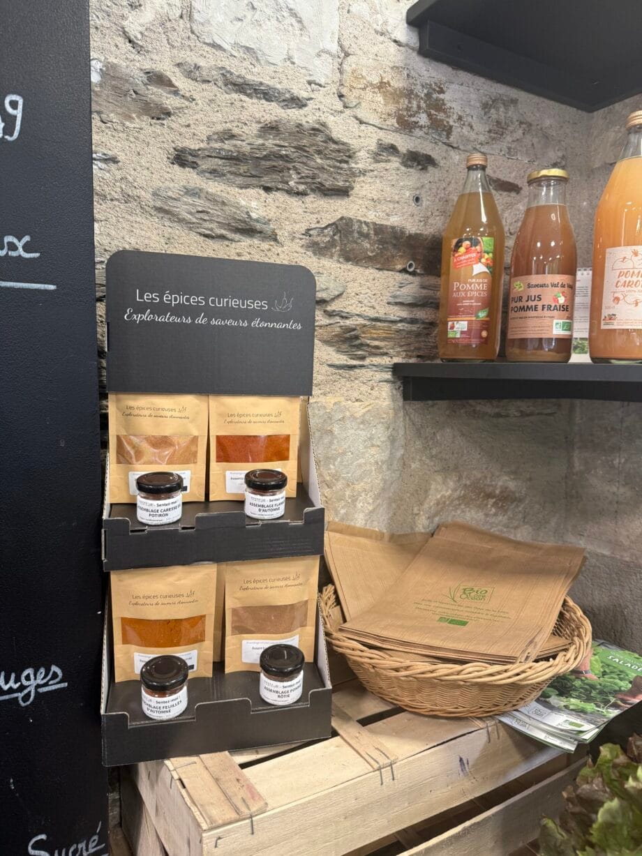 Épices et jus bio exposés sur étagères en pierre, mettant en valeur des saveurs uniques et naturelles dans une boutique.