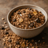 Bol de granola croustillant avec pépites de chocolat et céréales, posé sur une surface rustique.
