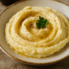 Purée de pommes de terre crémeuse avec beurre fondu et persil frais dans une assiette.