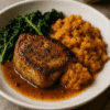 Plat de porc rôti avec purée de pommes de terre douce et épinards sautés dans une assiette blanche.