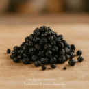 Amas de baies séchées sur une table en bois, texture rugueuse et couleur sombre.