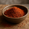 Bol de piment rouge moulu épicé sur table en bois, parfait pour assaisonner vos plats.