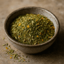Bol de fines herbes séchées et épices colorées sur une table en pierre, idéal pour assaisonner les plats.