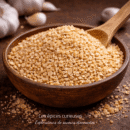 Bol en bois rempli d'ail séché et haché, sur une table en bois, avec des gousses d'ail en arrière-plan.