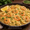 Spaghetti crémeux aux crevettes, citron et persil frais, servies dans une poêle noire.