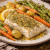 Plat de poisson rôti aux herbes avec légumes grillés : carottes, asperges, pommes de terre et tranche de citron.