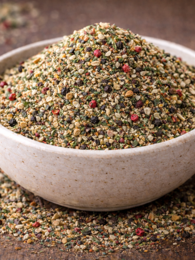 Bol de mélange d'épices variées sur fond rustique, parfait pour rehausser vos plats avec des saveurs riches et colorées.