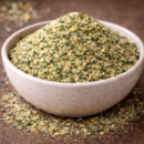 Bol rempli de gomasio aux graines de sésame et épices sur une table en bois.