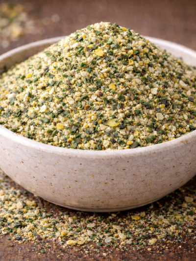 Bol rempli de gomasio aux graines de sésame et épices sur une table en bois.