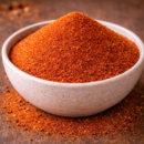 Bol de poudre de piment rouge épicée sur une table en bois, prêt pour la cuisine savoureuse et exotique.