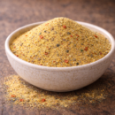 Bol de semoule épicée sur table rustique, parfait pour assaisonnement ou cuisine créative.