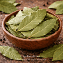 Bol en bois rempli de feuilles de laurier séchées, sur fond rustique avec grains de poivre noir et sel.