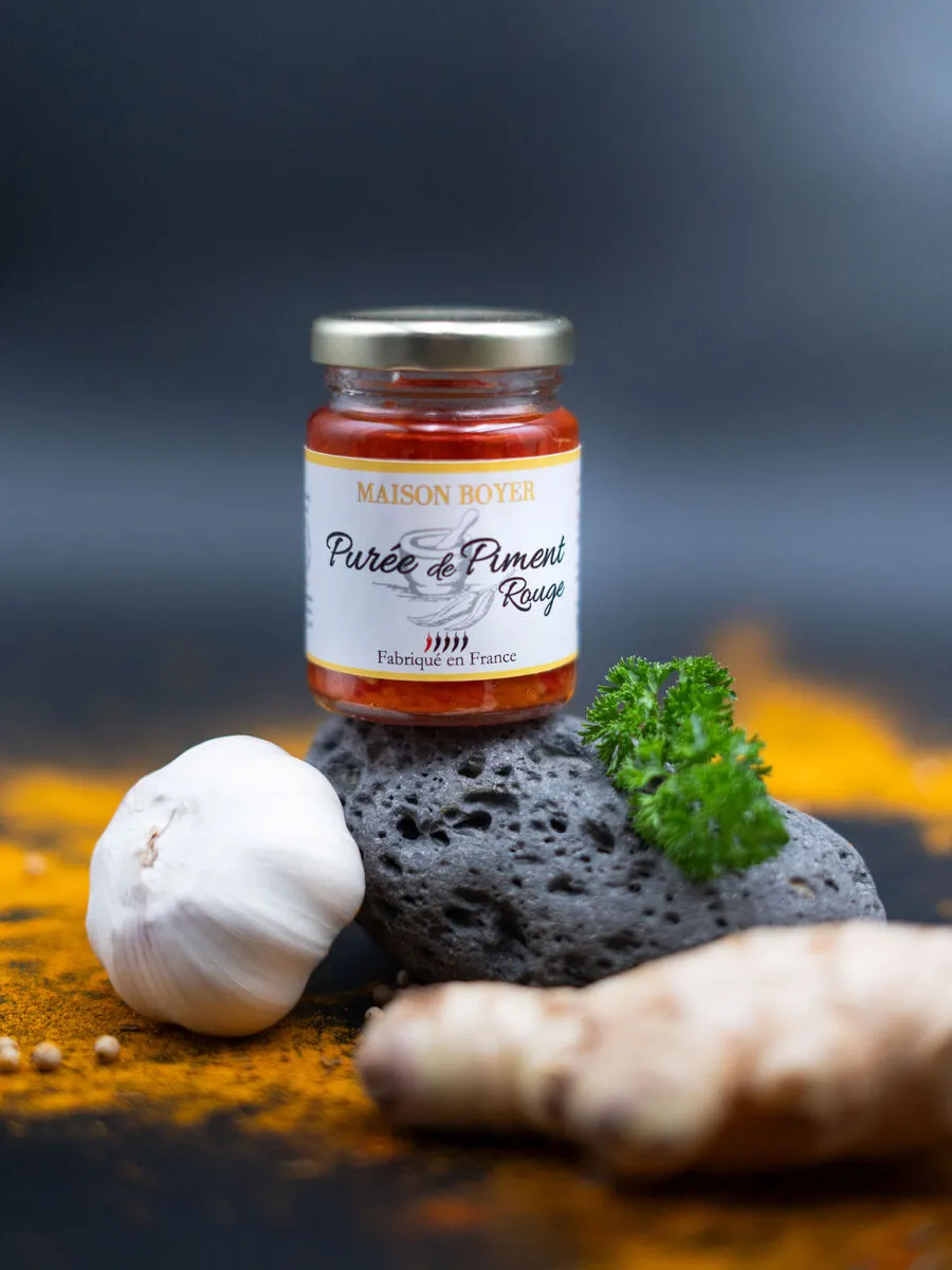 Bocal de purée de piment rouge Maison Boyer avec ail, gingembre et persil, fond coloré aux épices.